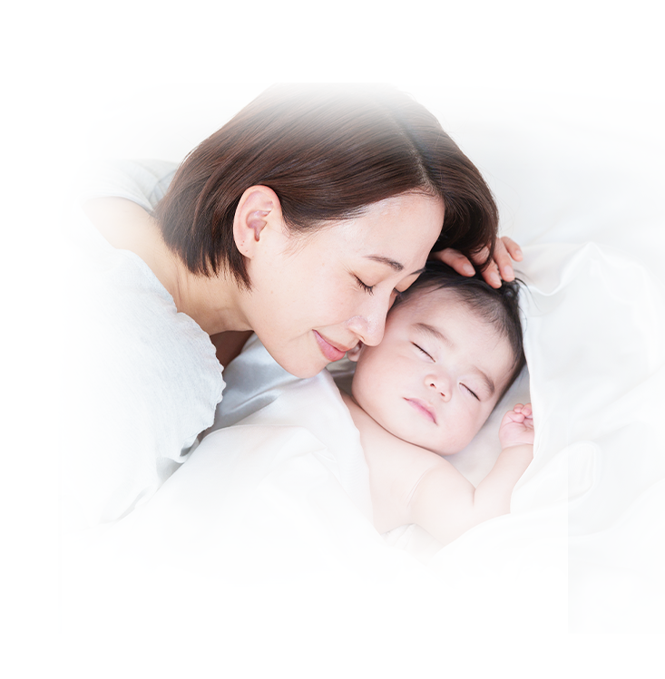 眠っている赤ちゃんと母親の笑顔