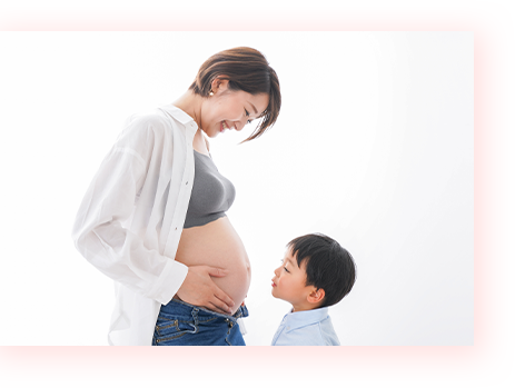 大きくなった妊婦の母親のお腹を見ている子ども